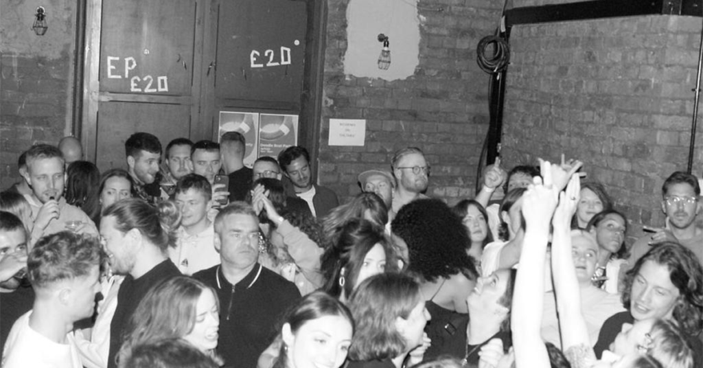 A black and white photo of a crowd partying at a Doodle MCR event at The Eagle Inn
